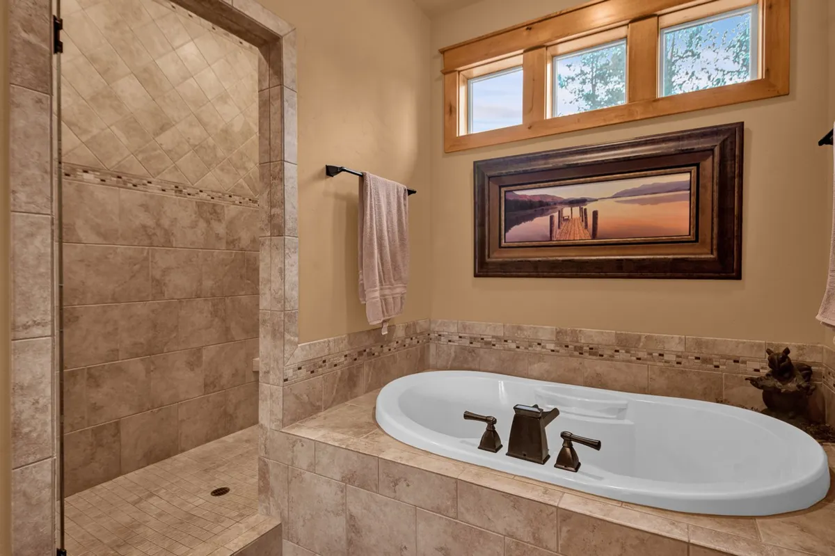 This photo showcases a calm, spa-like bathroom with a soaking bathtub, a modern shower area, and framed artwork on the wall. There is abundant natural light, contributing to a peaceful atmosphere perfect for relaxation after a day of exploring.