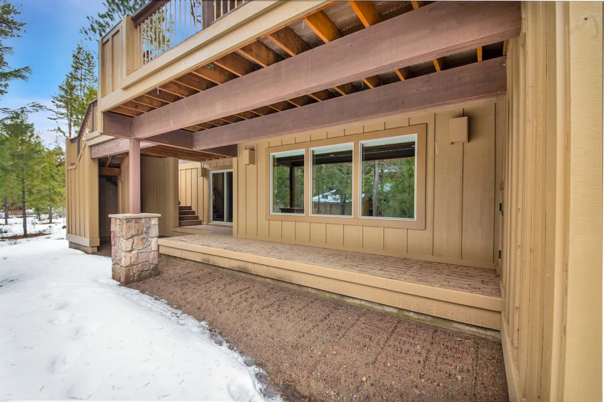 A spacious porch with large windows and a stone column, overlooking the natural scenery. The area invites group relaxation or social gatherings, whether summer or winter, seamlessly connecting indoor comfort to outdoor fun.