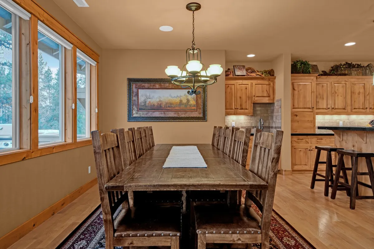 A warm, inviting dining area with a large table that seats ten, accented by a beautiful chandelier and tasteful wall art. The dining space is seamlessly connected to the kitchen, making it ideal for group meals and celebrations.
